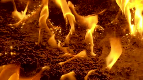 Close-up-of-intense-flames-sparkling-and-crackling-above-some-oil-soaked-ground