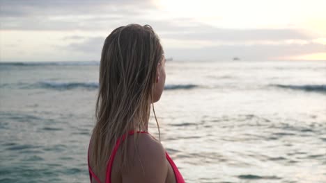 Schönes-Mädchen-Im-Roten-Badeanzug-Geht-Bei-Sonnenuntergang-Ins-Meer-Und-Lässt-Ihre-Harnds-Leicht-Durch-Das-Wasser-In-Hawaii-Laufen