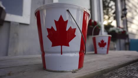 Eimer-Mit-Kanadischer-Ahornblattflagge-Auf-Einem-Cottage-Deck,-Glücklicher-Kanada-Tag