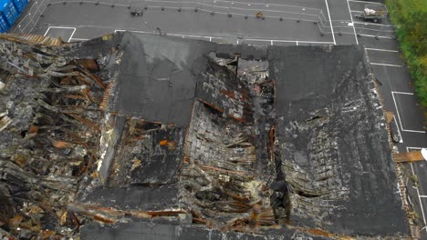 Aerial-view-of-remains-of-large-roof-destroyed-by-fire,-zooming-shot