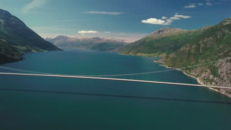 Panning-reveal-drone-shot-of-a-suspension-bridge-over-a-Fjord-on-a-sunny-day