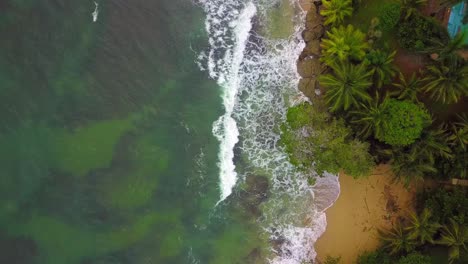 Slow-drone-flyover-of-the-clear-ocean-on-the-left-side,-with-views-of-the-reef