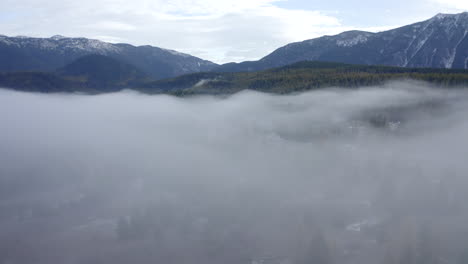 Aerial-Shot-Rising-Above-a-Thick-Layer-of-Fog-to-Reveal-a-Beautiful-Mountain-Landscape-on-a-Cold-Morning-in-Montana