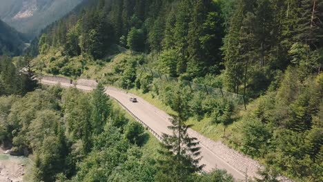 Grúa-Hacia-Abajo-De-Un-Automóvil-Que-Conduce-Por-Una-Carretera-De-Montaña-Rodeada-Por-Un-Bosque