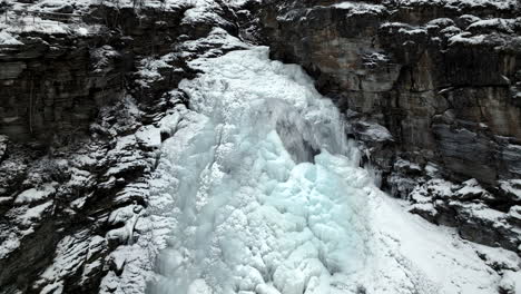 Pullback-On-Frosted-Waterfall-From-Rugged-Cliffs-During-Winter-In-Northern-Norway