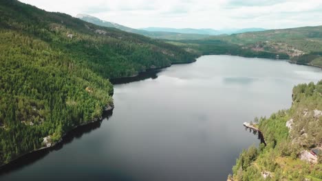 Pan-drone-shot-over-a-lake-surrounded-by-a-forest