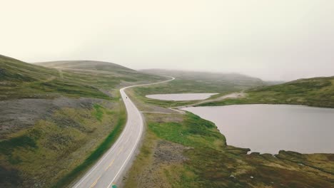 Forward-drone-shot-over-lakes-next-to-Nordkapp-following-a-motorcycle-from-distance