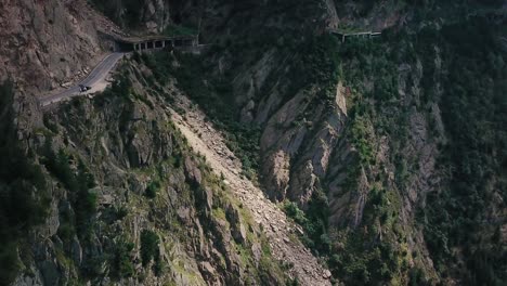 Elevating-drone-shot-of-a-mountain-road-next-to-a-cliff