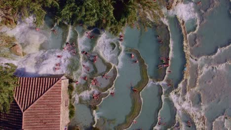 Tourist-people-relaxing-and-bathing-in-famous-sulfur-hot-springs-Saturnia,-top-down