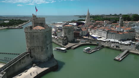 Ferry-boat-entering-in-old-port-of-La-Rochelle-with-Chain-and-Saint-Nicolas-towers,-France