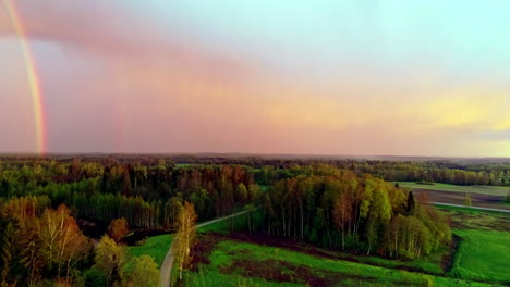 Aerial-shot-of-colorful-leaves-forest-with-roads,-grassland,-and-rainbow