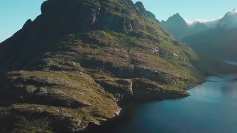 Panning,-tilt-down-drone-shot-of-a-rocky-hill-over-a-lake-in-Lofoten