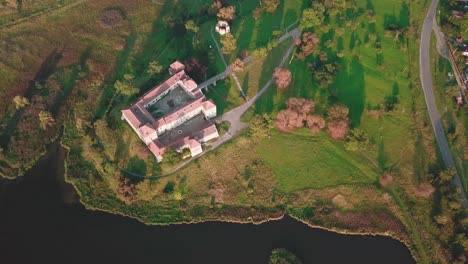 Forward-high-angle-drone-shot-of-a-castle-next-to-a-lake