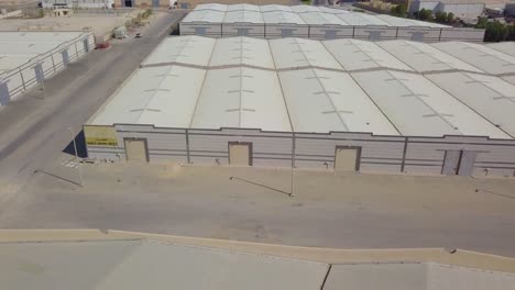 Lagerhallen-Nebeneinander-In-Der-Wüste-Mit-Ausgewiesenen-Parkplätzen-Und-Garagentoren