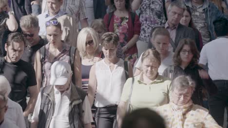 Handheld-footage-of-a-crowd-of-people-entering-a-subway-tunnel,-transitioning-from-the-bright-sunlight-to-the-shadows