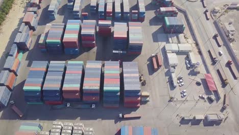 Eine-Flotte-Von-Lastwagen-Fährt-Mit-Bunten-Containern-Und-Ladern-Auf-Den-Riesigen-Containerhof-Und-Bereitet-Sich-Darauf-Vor,-Mit-Fracht-Beladen-Zu-Werden