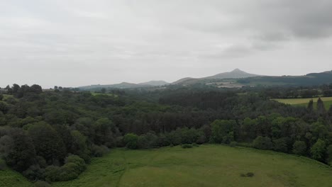 Draufsichtaufnahme-Der-Irischen-Berge-Im-Hintergrund,-Die-über-Ein-Grünes-Feld-Fliegen