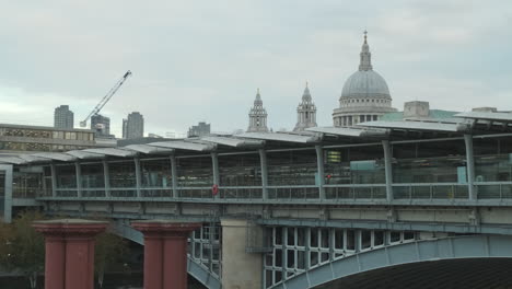London-Skyline,-Blackfriars-Station-Bridge-with-St-Pauls-Cathedral-and-Barbican-Centre-in-the-Background,-Old-Bridge-Pillars-in-Foreground