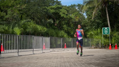 Cámara-Lenta-De-Un-Atleta-Adolescente-Con-Un-Traje-Rosa-Y-Azul-Corriendo-La-Etapa-Final-De-Una-Competencia-De-Triatlón-Con-Aspecto-Concentrado-Y-Cansado