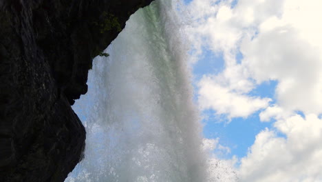 Unique-Steinsdalsfossen-Waterfall-that-you-can-walk-behind,-near-Steine,-Norway-tilt-down-from-behind-cascade,-in-ProRezHQ-4k