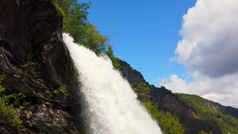Powerful-Steinsdalsfossen-Waterfall-near-Steine,-Norway-tilt-down,-sunny,-thundering,-beautiful,-4k-ProRezHQ-video