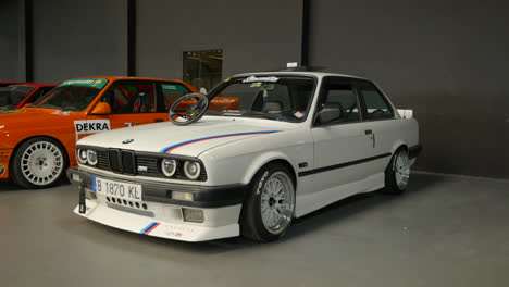 Elegante-Bmw-E30-Blanco-Con-La-Marca-Clásica-M-Stripe-En-El-Escaparate-De-La-Reunión-De-Fans-De-Autos-Clásicos-De-Barcelona