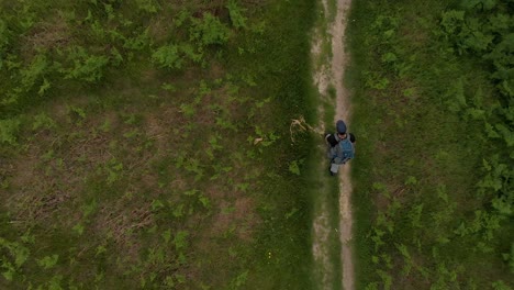 Top-down-view-of-lone-hiker-walking-on-a-path-in-a-green-field-carrying-a-large-backpack