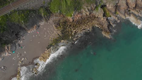 Top-down-panning-drone-shot-from-waves-hitting-the-Irish-beach-on-the-sea-of-Ireland