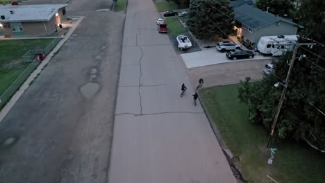 Three-young-boys-on-bikes-riding-through-urban-neighborhood-turning-into-a-driveway