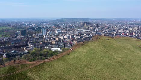 Panning-Over-The-Crags-at-Arthur's-Seat,-With-Edinburgh-Castle-and-Edinburgh-City-Centre-|-Edinburgh,-Scotland-|-4K-at-30-fps