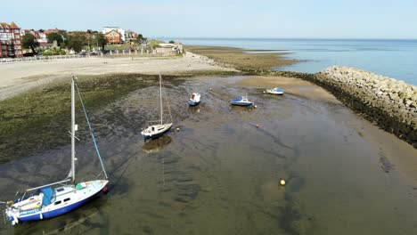 Aerial-view-boats-in-shimmering-low-tide-sunny-warm-Rhos-on-Sea-seaside-sand-beach-marina-descending-push-in