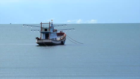 Un-Pequeño-Barco-De-Pesca-Local-De-Tailandia,-El-Barco-De-Madera-Estacionado-Solo,-Cielo-Azul-Despejado-Por-La-Mañana