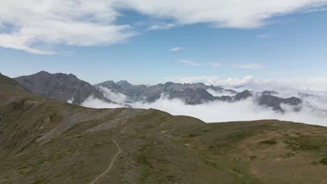 Aerial-view-of-the-path-on-top-of-the-mountain-with-the-clouds-surrounding-the-mountain-peaks-in-La-Cerdanya