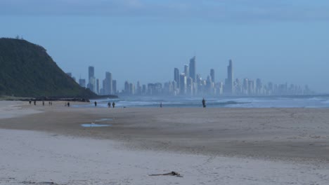 Menschen,-Die-In-Palm-Beach-Spazieren-Gehen---Skyline-Der-Goldküste-Im-Hintergrund---Touristenattraktion-In-Queensland,-Australien---Totale