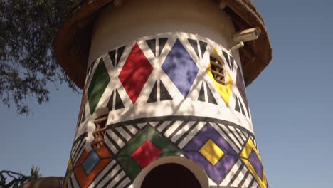 Tracking-shot-moving-out-of-Ndebele-painted-hut-revealing-patterns