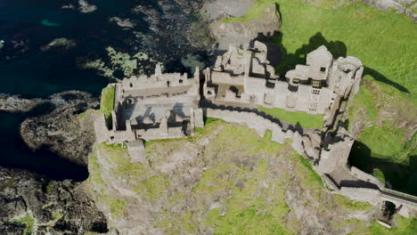 Irlanda---Ruinas-Antiguas-Del-Castillo-Medieval-De-Dunluce,-Drone-Aéreo-Inclinado-Hacia-Abajo