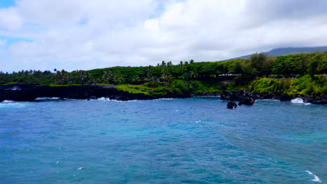 Tilt-up-from-black-lava-rocks-to-beautiful-Keawaiki-Bay-and-blue-Pacific-ocean-waves-and-Sea-Arch-on-Road-to-Hana,-Maui,-Hawaii,-4k-ProRozHQ