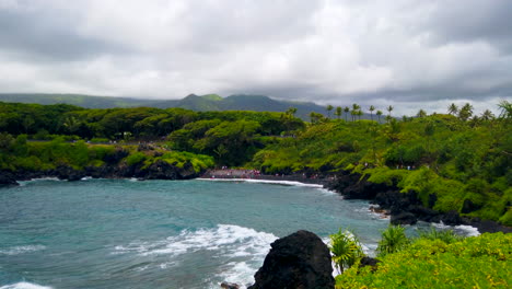 Black-Sand-Honokalani-Beach,-fast-pan-from-blue-Pacific-Ocean's-Keawaiki-Bay-on-Road-to-Hana,-Maui,-Hawaii,-4k-ProRezHQ