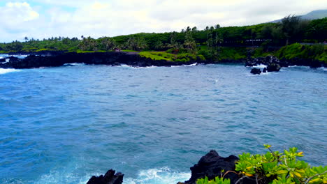 Beautiful-pan-from-blue-Pacific-Ocean,-past-Keawaiki-Bay-and-its-Sea-Arch-to-Black-Sand-Honokalani-Beach-on-Road-to-Hana,-Maui,-Hawaii,-4k-ProRezHQ