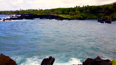 Pan-from-Honokalani-Black-Sand-Beach-to-sea-arch-of-Keawaiki-Bay-and-beautiful-blue-Pacific-Ocean-on-Road-to-Hana,-Maui,-Hawaii,-4k-ProRezHQ