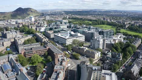 Aerial-shot-over-Edinburgh-University-buildings-and-the-Meadows,-towards-Arthurs-Seat,-on-a-sunny-day|-Edinburgh,-Scotland-|-4K-at-30-fps
