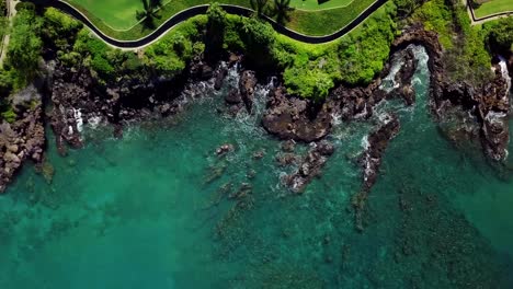 A-drone,-birds-eye,-aerial-top-down-view-of-beautiful-teal-waters-crashing-against-the-coast-along-the-edge-of-walking-paths-and-beautiful-homes-in-Wailea-on-the-southern-coast-of-Maui,-Hawaii