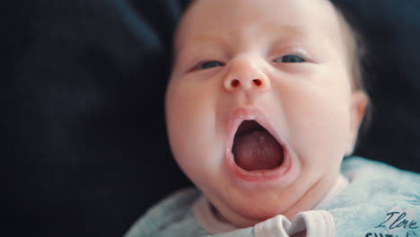 A-newborn-baby-who-is-rocking-and-yawning-lying-on-a-black-background