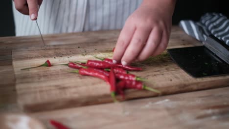Red-Chilli-Peppers-being-prepared-and-chopped-on-a-wooden-block