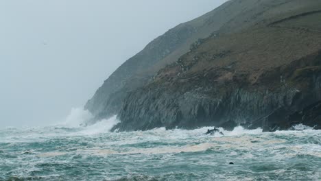 Spritzende-Wellen-An-Der-Stürmischen-Irischen-Küste-Mit-Möwen-Am-Himmel