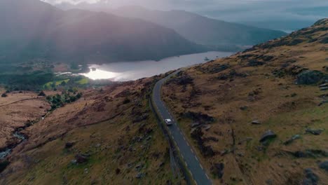 Car-driving-on-a-road-by-the-mountains-and-a-lake-aerial
