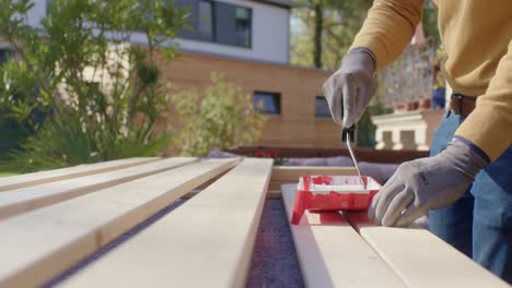 Craftsman-is-putting-the-paint-roller-into-paint-tray-and-is-also-painting-the-wood