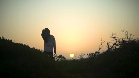 Breite-Sonnenuntergangsaufnahme-Eines-Mädchens-In-Der-Natur,-Das-Mit-Den-Fingern-Durch-Ihr-Haar-Fährt,-Während-Sie-Den-Sonnenuntergang-Beobachtet
