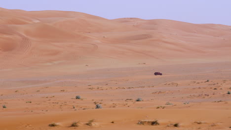 Vehículo-Que-Viaja-En-Un-Paisaje-Desierto-Remoto-Cerca-De-La-Reserva-Natural-De-Rocas-Fósiles-En-Sharjah,-Emiratos-Árabes-Unidos