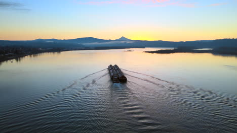 Drone-flying-above-water-and-slowly-lowering,-looking-at-a-beautiful-scenery-of-a-large-boat-laying-still-on-a-lake-during-sunrise